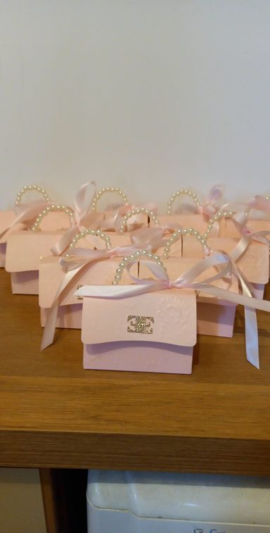 Several small pink gift boxes with ribbons arranged on a wooden surface.