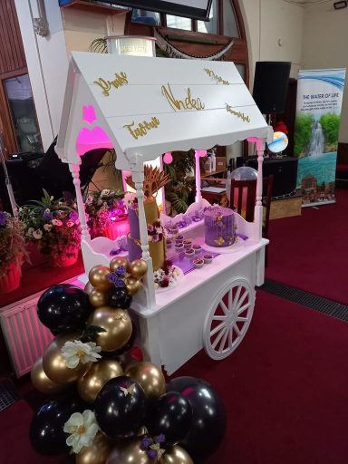 Decorative cart with balloons and sweets, adorned with gold embellishments.