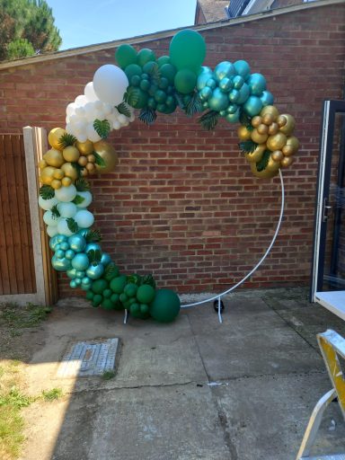 A circular balloon arch in green, white, and gold decorations.